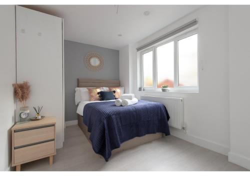 a bedroom with a bed with a blue blanket and a window at Splendid and Comfy 1 bedroom apartment in London