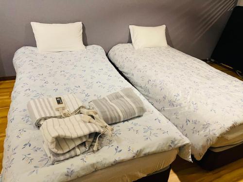 duas camas com toalhas e uma bolsa em Namba Shinsaibashi 10 mins Reiko guest house em Osaka