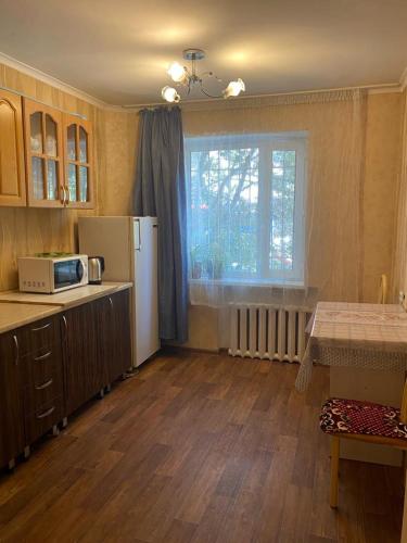 a kitchen with a refrigerator and a table and a window at Тихая теплая уютная однушка in Karagandy