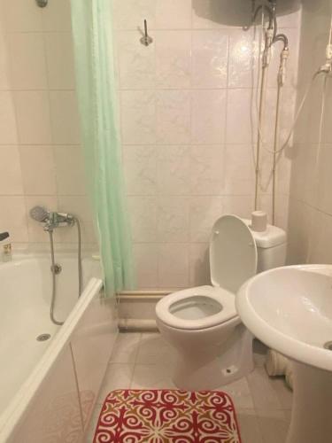 a white bathroom with a toilet and a sink at Тихая теплая уютная однушка in Karagandy