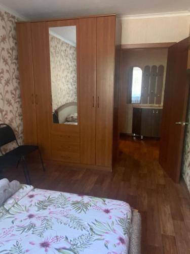a bedroom with a bed and a cabinet with a mirror at Тихая теплая уютная однушка in Karagandy