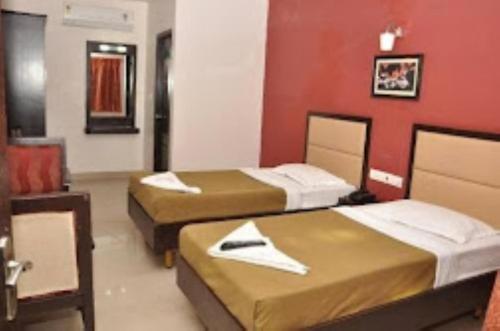 two beds in a room with red walls at Hotel Sri Arulmuthu Residency Madurai in Madurai