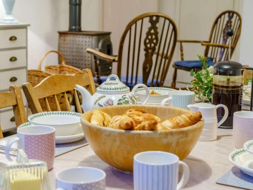 a table with a bowl of pastries on a table with cups at 4 Bed in Monmouth 42868 in Cwmcarvan