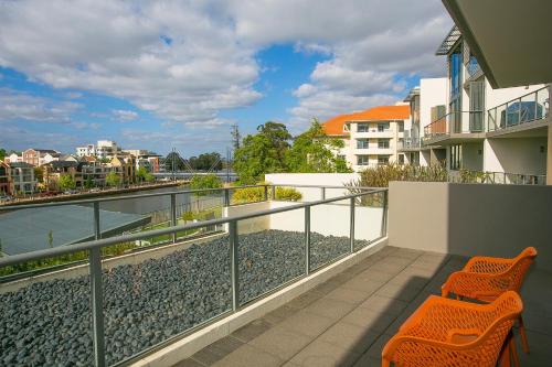 a balcony with two chairs and a view of the water at East Perth Suites Hotel in Perth
