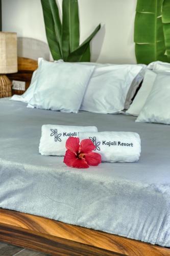 a bed with two pillows and a red flower on it at Kajali Siargao in General Luna