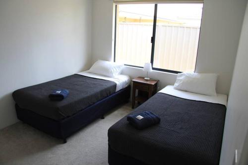 two beds in a small room with a window at Southern River Family Accommodation. Free WiFi in Perth