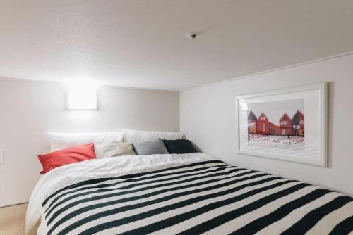 a white bedroom with a bed with a striped blanket at LAKE VIEW LOFT JAMSIL in Seoul