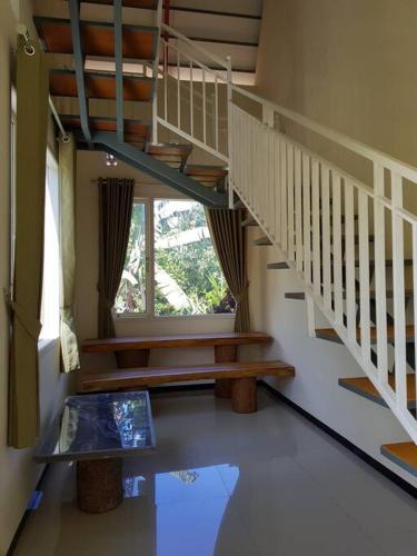 a staircase in a house with a table and a window at Villa Songgokerto Batu in Songgoriti