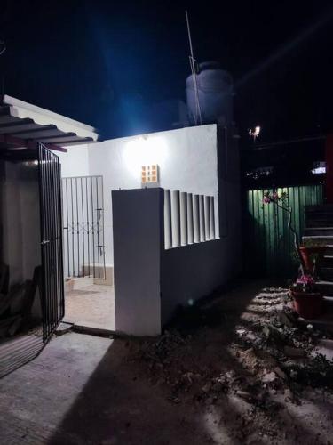 a white building with a gate at night at Depa en el corazón de Progreso a 2min del malecón. in Progreso