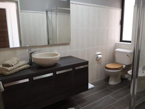 La salle de bains est pourvue d'un lavabo, de toilettes et d'un miroir. dans l'établissement Apartment in Swieqi with communal pool, à Tal-Għoqod