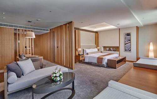 台中市にあるミレニアム ホテル タイチュンのベッドとリビングルームが備わるホテルルームです。