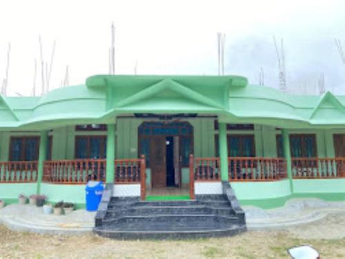 una pequeña casa verde con escaleras delante en Ninashi Homestay Wakro, 