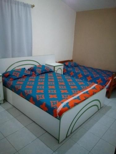 a bedroom with a bed with a blue and orange comforter at Pritanier in Flic-en-Flac