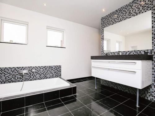 La salle de bains est pourvue d'une baignoire et d'un miroir. dans l'établissement Holiday home Bogense XXVI, à Bogense
