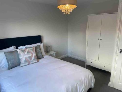 um quarto com uma cama branca com almofadas e um lustre em Nuneaton-GE Hospital 3 mins away em Nuneaton