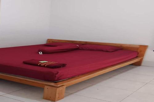 una cama de madera con sábanas rojas encima. en OYO Life 93015 Kos Anto, en Pawenang