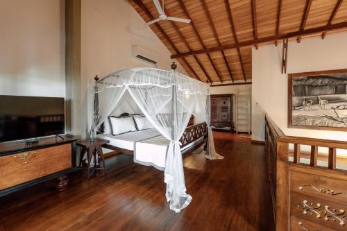 a bedroom with a canopy bed and a television at Pearl Divers Beachfront Apartment in Unawatuna