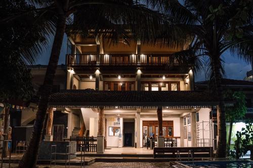 a house with a balcony on top of it at Pearl Divers Beachfront Apartment in Unawatuna