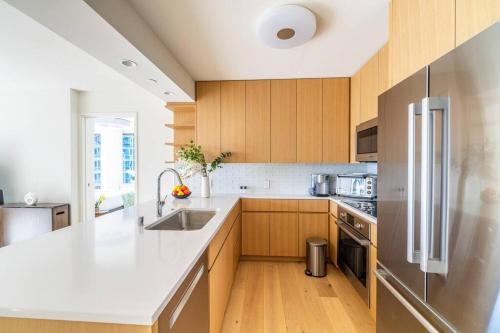a kitchen with wooden cabinets and a stainless steel refrigerator at Brand New! Luxurious Sky Ala Moana 2 Bed 2 Bath in Honolulu