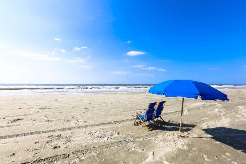 a blue chair and an umbrella on the beach at Surfscoter in Johns Island