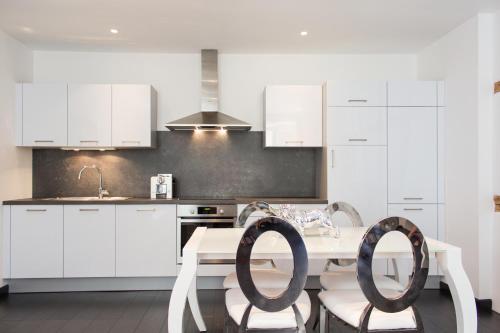 una cocina con armarios blancos y una mesa y sillas blancas. en MY SWEET HOMES - Appartements avec SPA, en Colmar