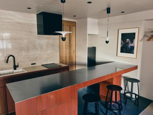 an open kitchen with black countertops and stools at illi Mani Shibuya in Tokyo