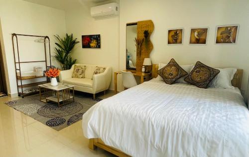 a bedroom with a large white bed and a chair at Căn hộ STUDIO VINHOMES GRAND PARK Quận 9 in Long Bình