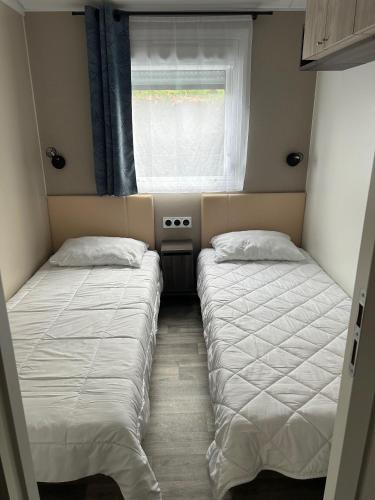 deux lits dans une petite pièce avec une fenêtre dans l'établissement Superb Mobilhome Cc379 Siblu Les Charmettes, aux Mathes