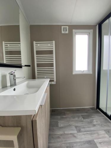 une salle de bain avec un lavabo blanc et une fenêtre dans l'établissement Superb Mobilhome Cc379 Siblu Les Charmettes, aux Mathes