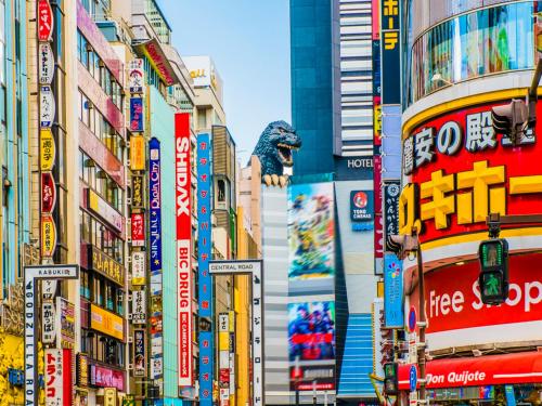 東京にあるアパホテル〈新宿 歌舞伎町中央〉の看板や建物が多く並ぶ賑やかな街道