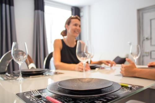 a woman sitting at a table with wine glasses at MY SWEET HOMES - Appartements avec SPA in Colmar