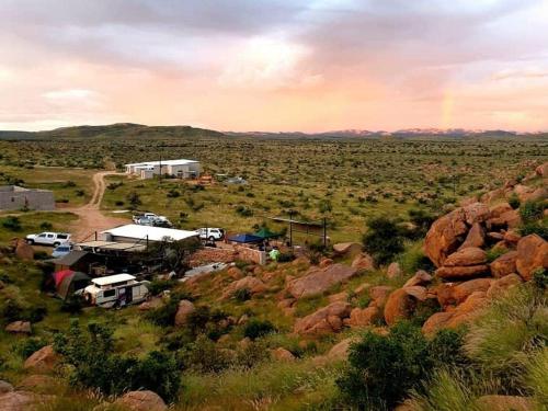 a group of vehicles parked in a field with a rainbow at Stofpad Lodge and Camping in Guisis