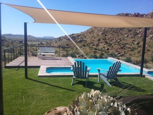 eine Terrasse mit 2 Stühlen und einem Pool in der Unterkunft Stofpad Lodge and Camping 