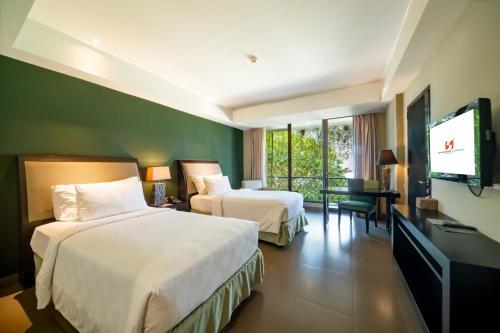 a hotel room with two beds and a flat screen tv at Swiss-Belhotel Rainforest in Kuta