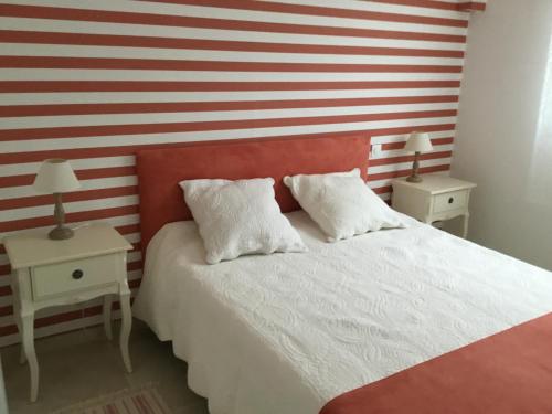 ein Schlafzimmer mit einer rot-weißen gestreiften Wand und einem Bett in der Unterkunft Le Clos des Gazanias in Grignols