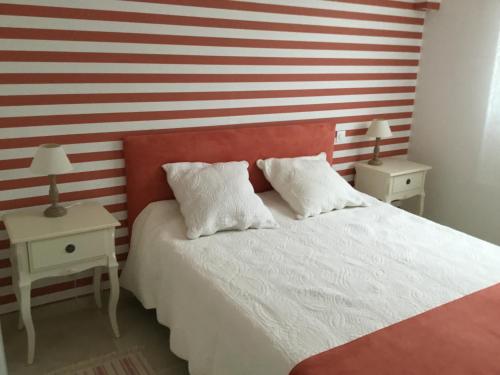 una camera da letto con un letto e una parete a righe rosse e bianche. di Le Clos des Gazanias a Grignols