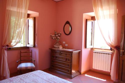 a bedroom with a bed and a dresser and two windows at Fattoria Antognoni in Reggello
