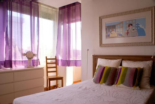 a bedroom with a bed with purple curtains and a chair at Alameda Lisbon Light in Lisbon