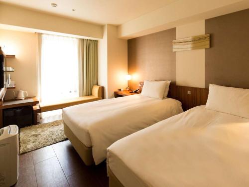 Hotel Resol Ikebukuro في طوكيو: غرفة فندقية بسريرين ونافذة