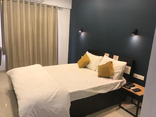 um quarto com uma cama com lençóis brancos e almofadas amarelas em Hooliv 7 Avenues G Block em Pune