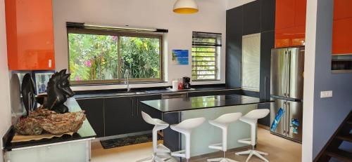 eine Küche mit einer Theke mit Hockern und einem Fenster in der Unterkunft Villa Heirama in Punaauia