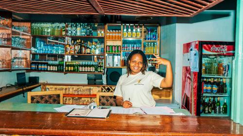 a woman standing behind a counter in a bar at Isange Paradise Resort in Ruhengeri