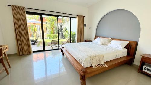 a bedroom with a bed and a large window at Villa Niu Center Canggu - FattyLion in Canggu