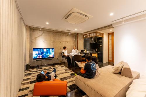 um grupo de crianças sentadas numa sala de estar a ver televisão em Tre casa hotel KAMAKURA em Kamakura