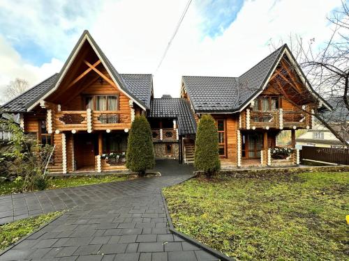 una gran casa de madera con un camino delante de ella en Oberig Apartmens, en Vorokhta