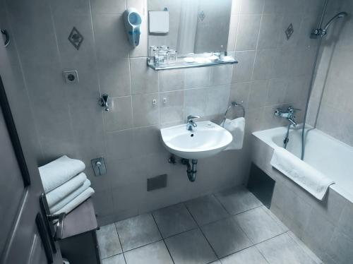 a white bathroom with a sink and a tub and a sink at Hotel Vienna in Zagreb