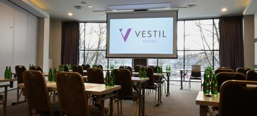 a conference room with tables and chairs and a screen at Vestil Hotel in Piotrków Trybunalski