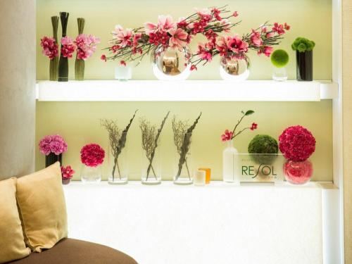 a shelf with vases filled with flowers and plants at Hotel Resol Ikebukuro in Tokyo