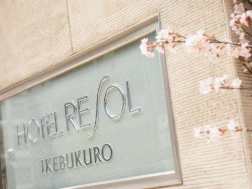 a sign on the side of a building with flowers at Hotel Resol Ikebukuro in Tokyo