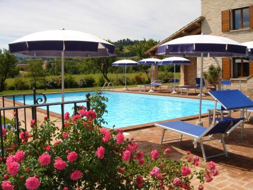 - une piscine avec 2 chaises, des parasols et des fleurs roses dans l'établissement Parco Ducale Country House, à Urbania